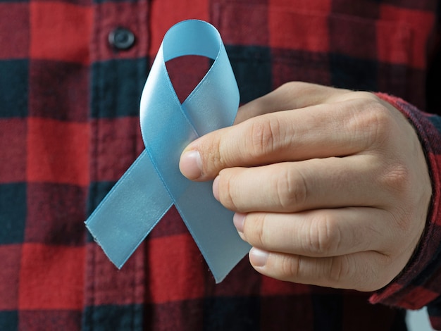 Foto uomo in una camicia a quadri che tiene un nastro blu