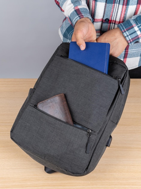 A man in a plaid shirt takes out a blue notebook from a stylish backpack for work