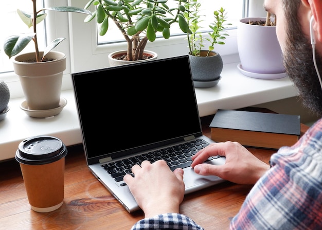 A man in a plaid shirt uses a laptop with a blank screen