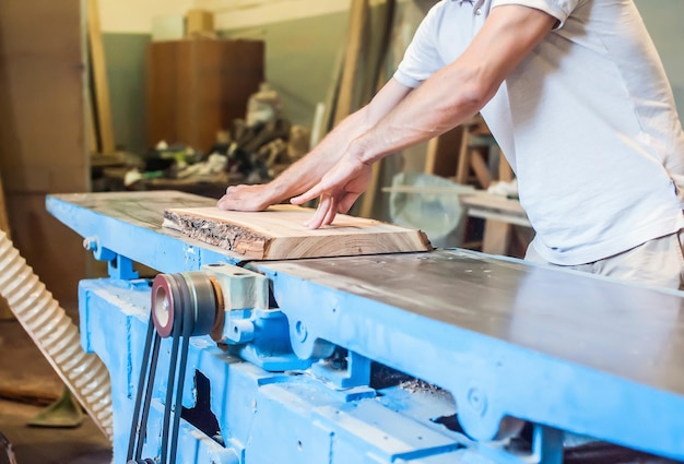 Foto un uomo pianta una tavola su un grande giunto industriale in un laboratorio di falegnameria