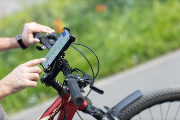 Man planning route using gps navigation application in mobile phone on his bicycle bike