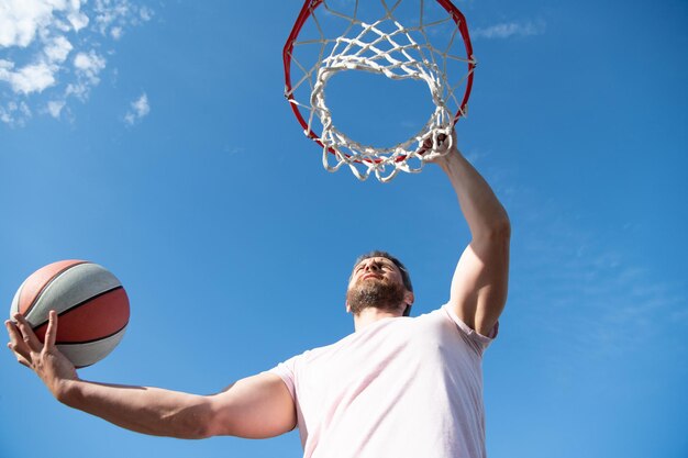 Man play basketball outdoor. man jump to throw the ball. guy\
play basketball. guy hold sport ball. adult player or coach.\
energetic sport. summer sports activity.