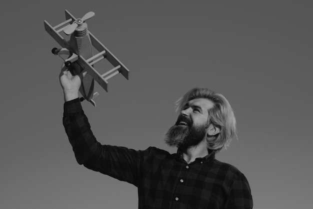 Man play with toy plane Bearded crazy man with a wooden airplane Dreams of flying Travel concept