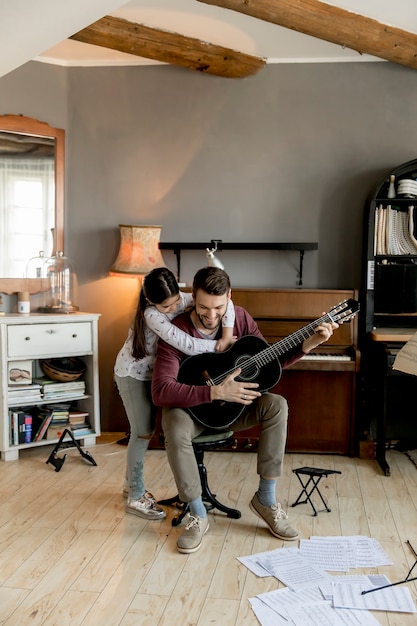 Man playing acoustic guitar for daughter in living room at home