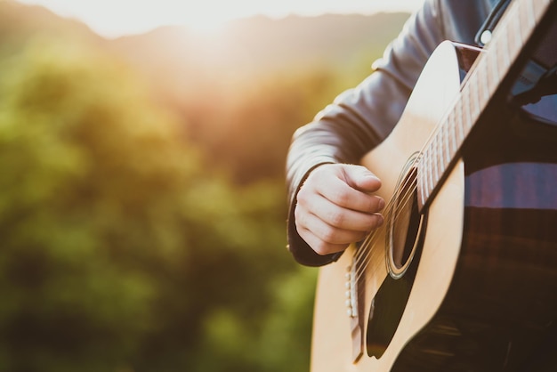 Uomo che suona la chitarra acustica in natura in una giornata di sole