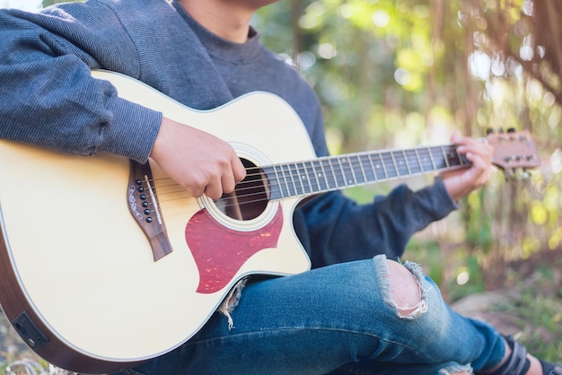 Man playing an acoustic guitar in the park Closeup