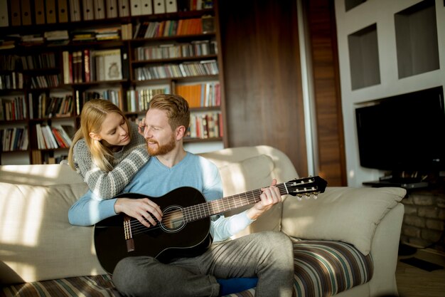 Man playing acoustic guitar on the sofa 