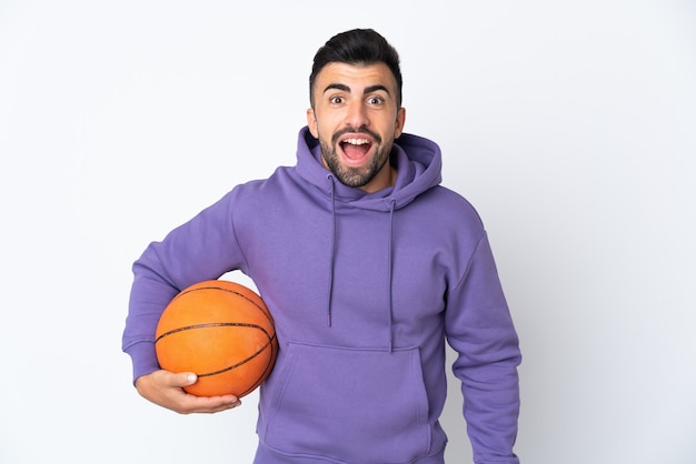 Man playing basketball over isolated white wall with surprise facial expression