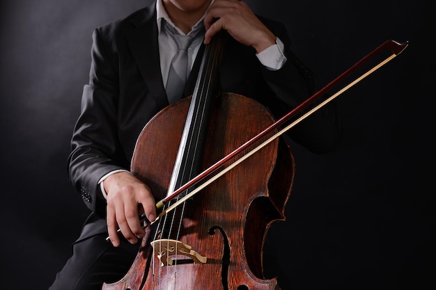 Man playing on cello on dark background