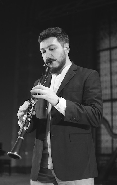 Photo man playing clarinet while standing at studio