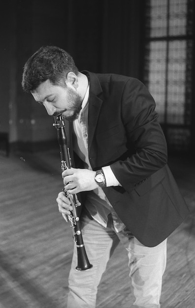 Photo man playing clarinet while standing at studio