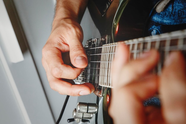 Man playing electric guitar close up view very shallow depth of field image cinematic effect applied