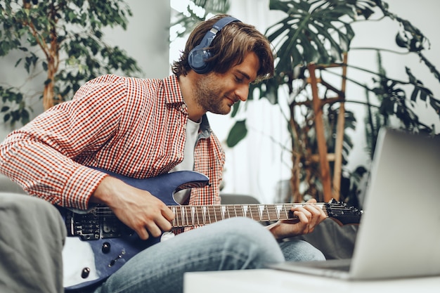 Photo man playing electric guitar and recording music into laptop