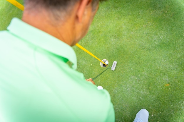 Uomo che gioca a golf dettaglio di un colpo con il putter sulla vista verde dall'alto