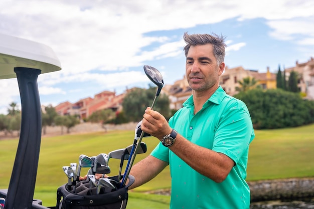 Man playing golf at golf club checking golf clubs in buggy before starting to play