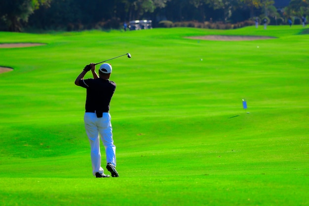 Foto uomo che gioca a golf su un campo da golf, pro golf mettendo la pallina da golf nella buca.