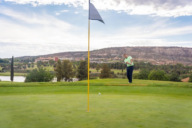 A man playing golf hitting the ball onto the green