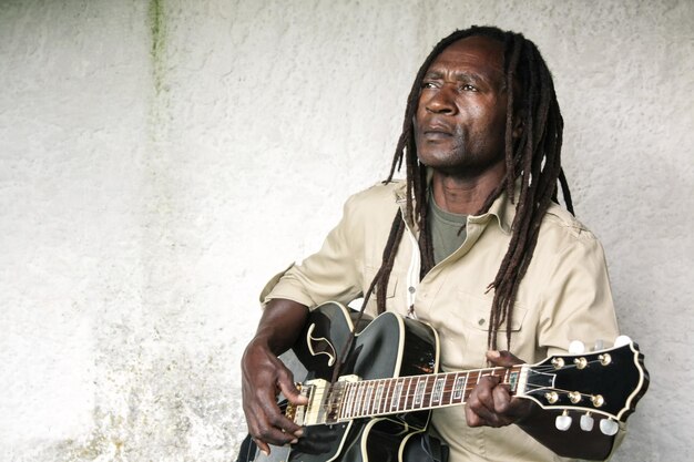 Man playing guitar against wall