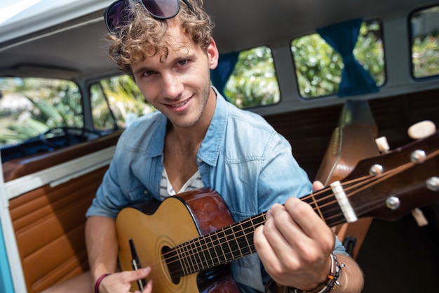 Man playing guitar in campervan