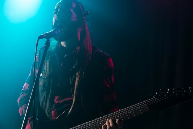 Man playing guitar and holding a microphone