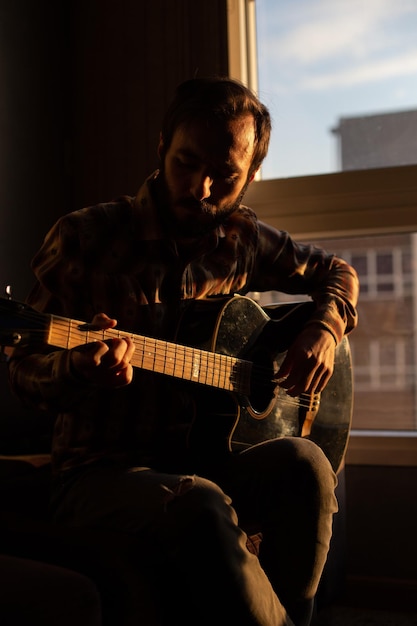 Foto uomo che suona la chitarra a casa