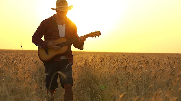 Photo man playing guitar on land against sky during sunset