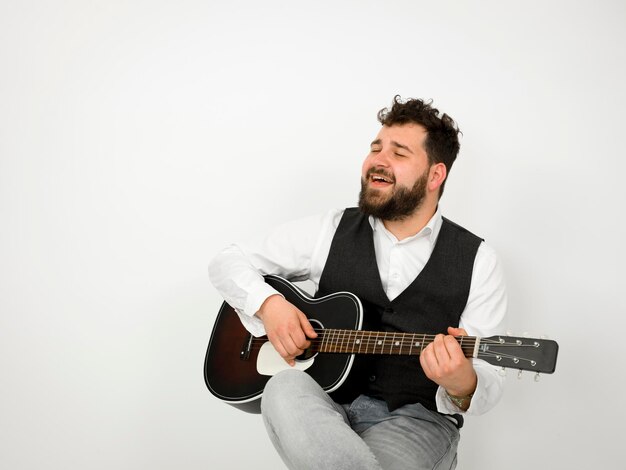 Foto uomo che suona la chitarra mentre canta su uno sfondo bianco