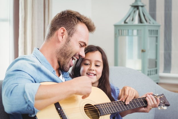 Uomo che suona la chitarra con sua figlia a casa