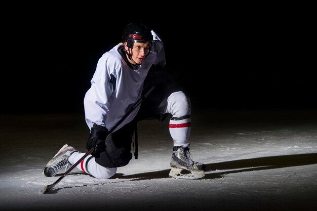 Photo man playing ice hockey against black background