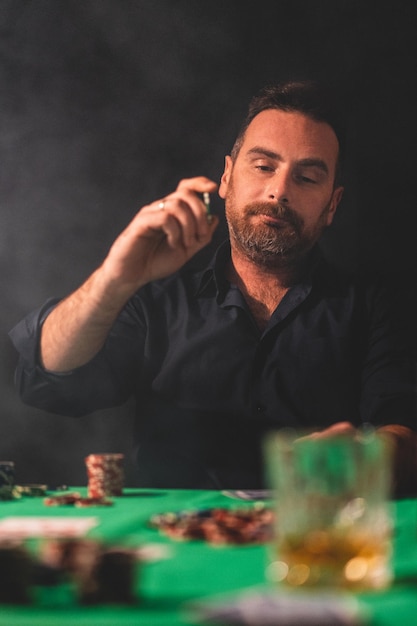 Фото Мужчина играет в покер за столом на черном фоне