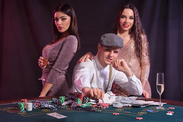 Человек, играющий в покер в казино, сидит за столом со стопками карточек с фишками и празднует победу с t