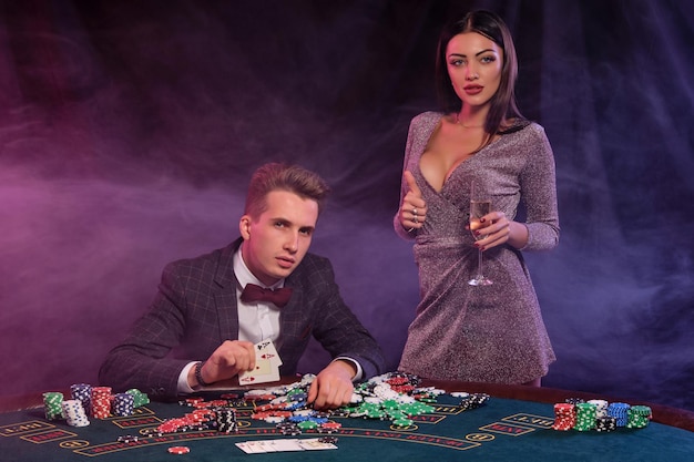 Man playing poker at casino sitting at table with stacks of chips money champagne cards celebrating