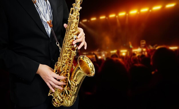 A man playing a saxophone with a crowd in the background.