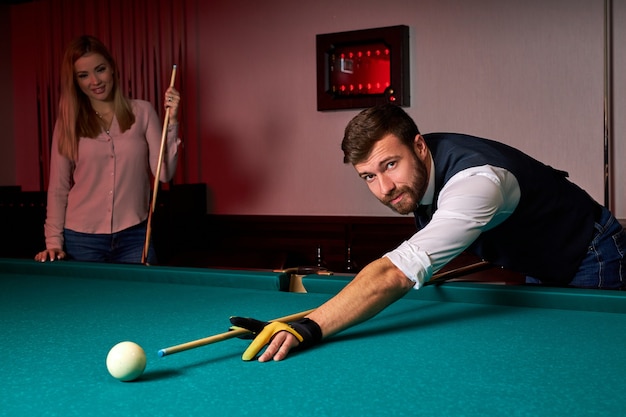 Man playing snooker, lining to hit ball on pool billiards table. pleasant pastime in the bar after work