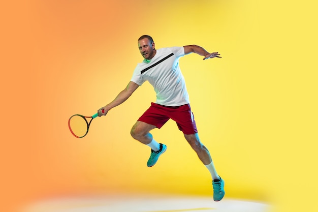 Человек играет в теннис, изолированные на фоне студии в неоновом свете