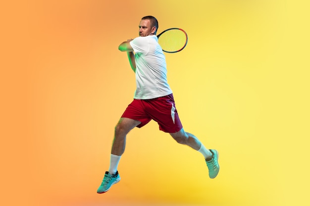 Photo man playing tennis isolated on studio background in neon light