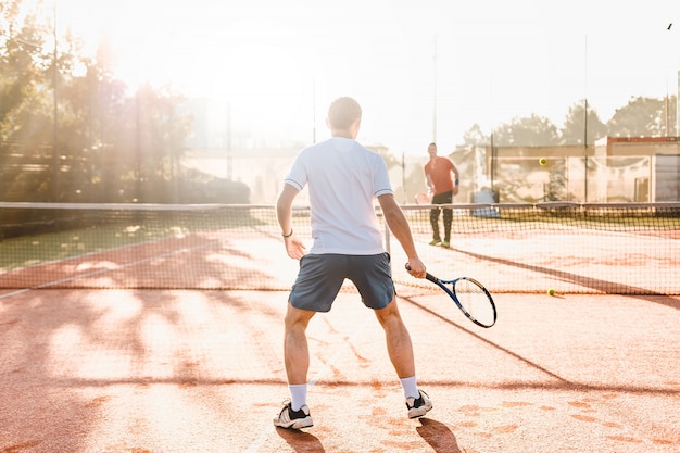 Man playing tennis in the morning in sunlight