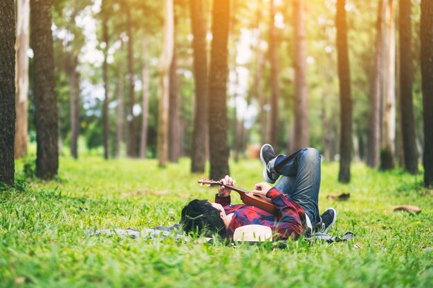 A man playing ukulele while lying down on a green yard