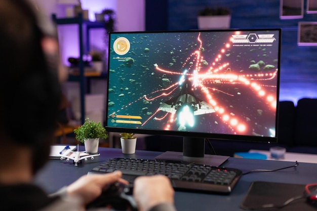 Close up of gamer holding controller and playing video games on computer.  Woman using joystick to play online digital games in front of monitor.  Person with modern gaming equipment Stock Photo 