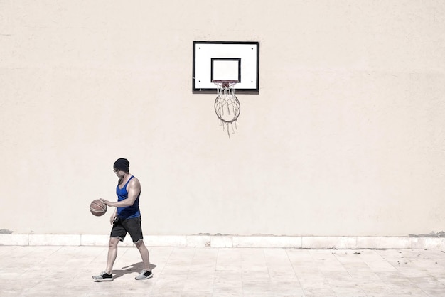 Man playing with basketball on court during sunny day