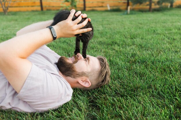 Foto uomo che gioca con il gatto sdraiato sull'erba