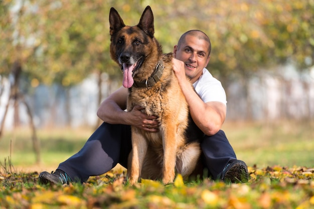 公園で犬のジャーマンシェパードと遊ぶ男