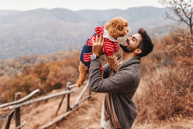 Foto uomo che gioca con il cane in natura. sullo sfondo la foresta e le montagne. tempo d'autunno.