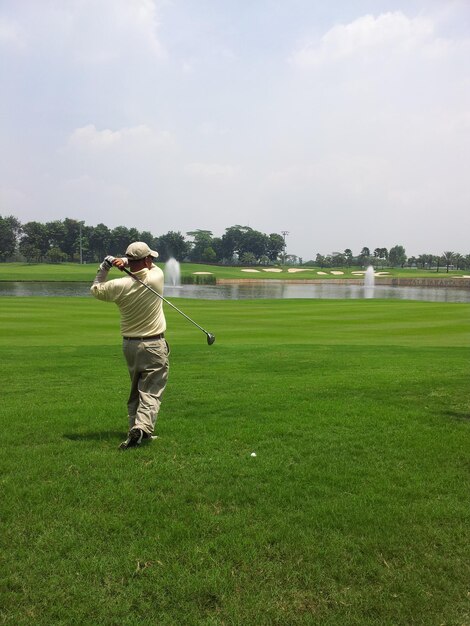 Photo man playing with golf on course against sky
