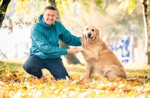 公園で彼の犬のゴールデン ・ リトリーバーと遊ぶ男