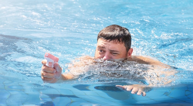 Фото Мужчина играет с водяным пистолетом в бассейне