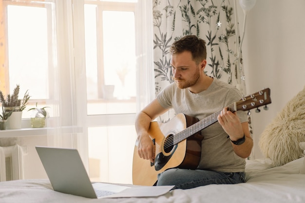 Man plays an acoustic guitar in an online lesson