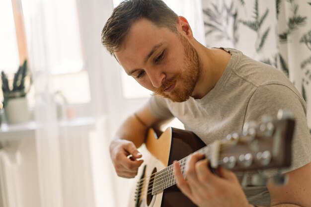 Photo man plays an acoustic guitar in a room at home