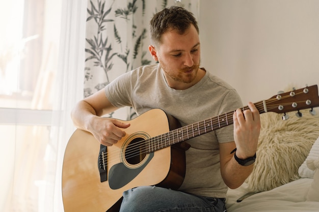 Man plays an acoustic guitar in a room at home