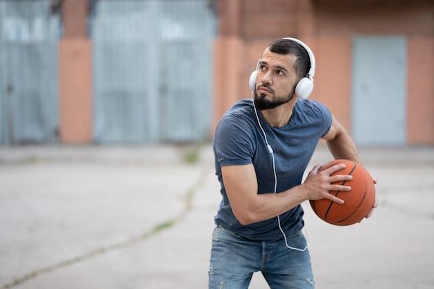 A man plays basketball in the street yard during the day